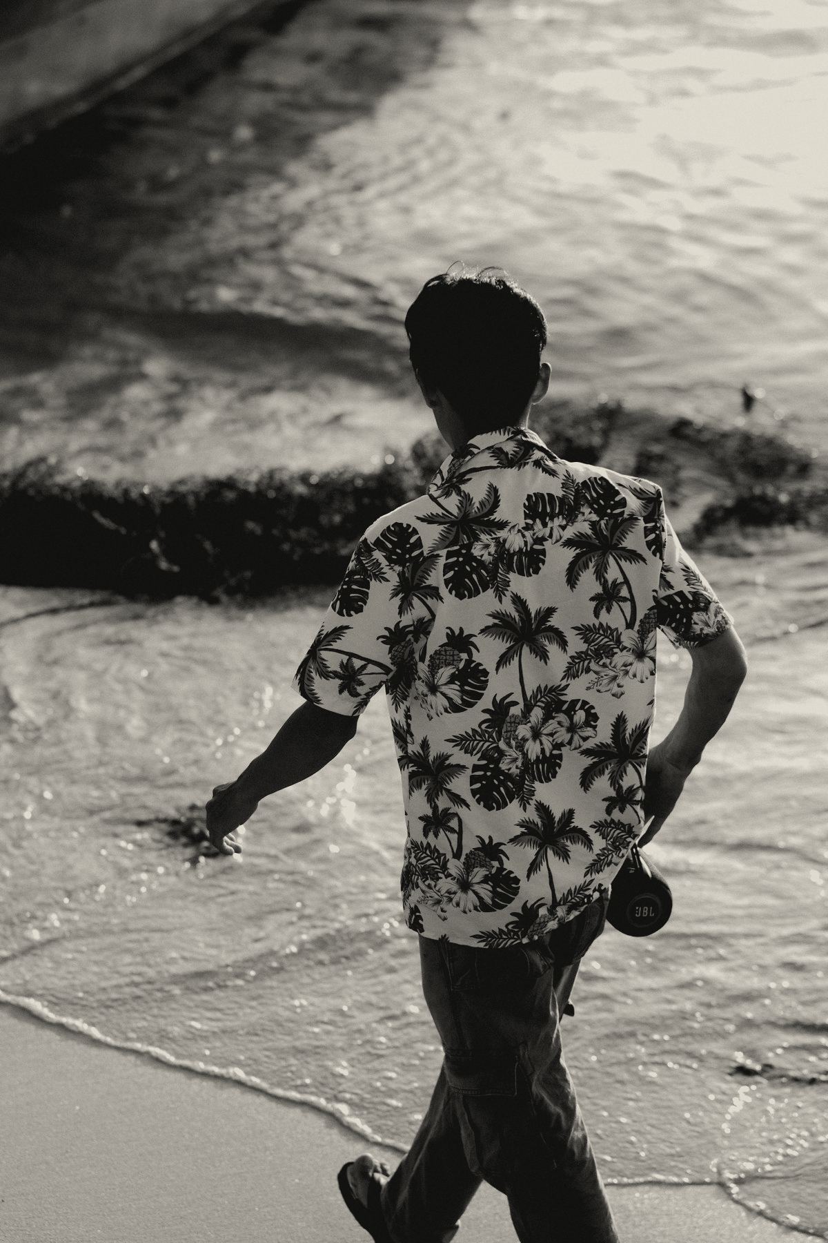 Man in a print camp shirt walking along the shoreline