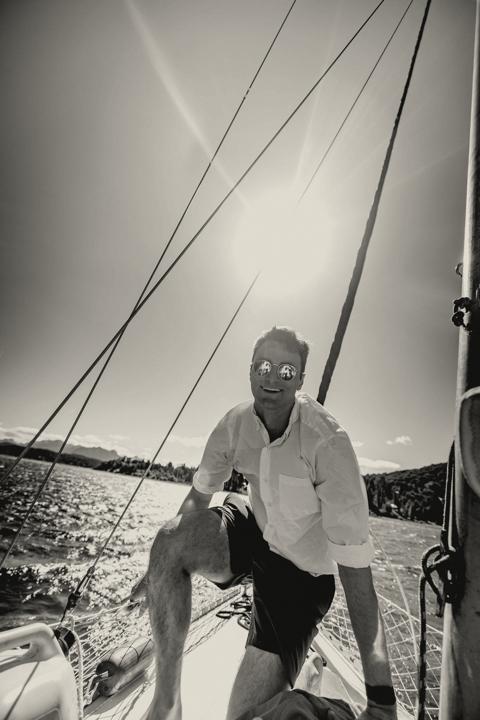 Man trimming the sails aboard a classic wooden gaff-rigged sailboat